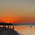Personas contemplan el atardecer en la playa